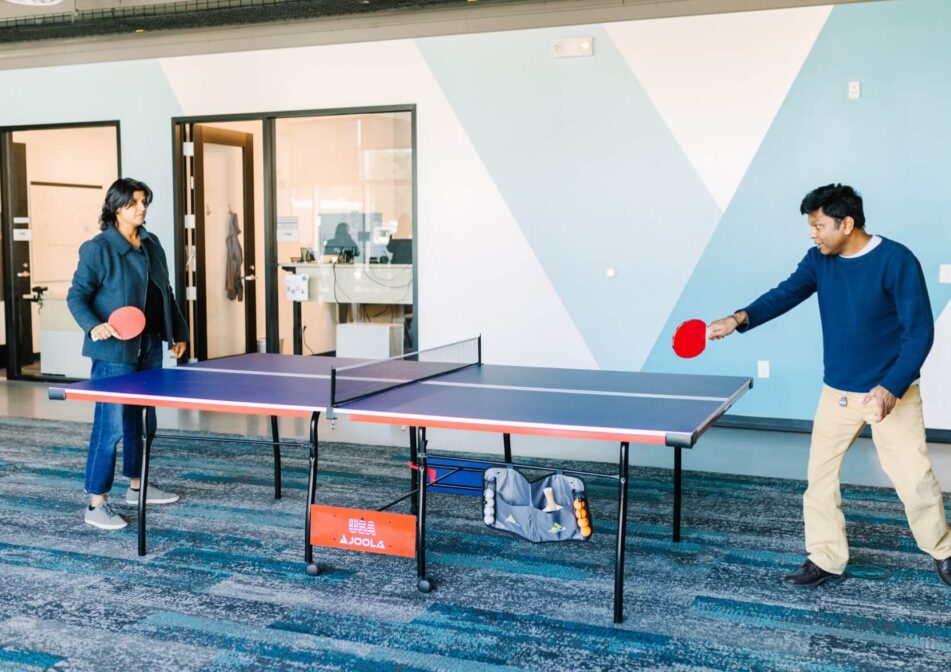 Ribometrix team members playing ping pong in game room